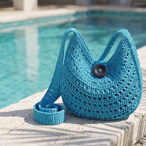 May include: A bright turquoise crochet shoulder bag featuring an open-work stitch pattern, a single long strap, and a large, dark circular button closure centered at the top opening. The bag has a rounded, crescent-like shape and a textured finish.
