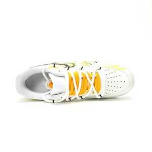 May include: White athletic shoe with yellow accents, including laces and design elements. The shoe features a perforated toe box and a padded tongue. The overall design is sporty and modern, suitable for various activities.