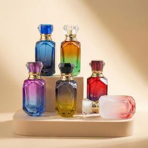 Puede incluir: Una colección de frascos de perfume en varios colores, incluyendo azul, naranja, verde, morado, amarillo y rojo. Cada frasco tiene un cuello dorado y una tapa facetada en forma de joya. Un frasco está tumbado de lado.