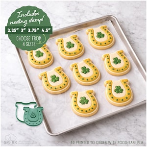 May include: A tray of horseshoe-shaped cookies decorated with green shamrocks and yellow accents. The cookies are on parchment paper. The image includes text that says "Includes nesting stamp!" and "Choose from 4 sizes".