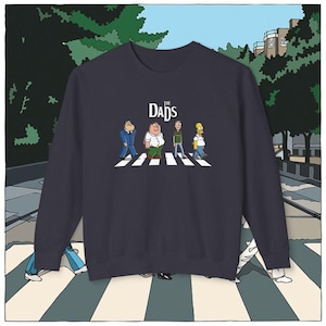Op de afbeelding: Marineblauwe sweatshirt met een parodie op de Abbey Road albumhoes van The Beatles. De afbeelding toont cartoonvaders die een zebrapad oversteken, met de tekst "The Dads" erboven. Het is een crew neck model.