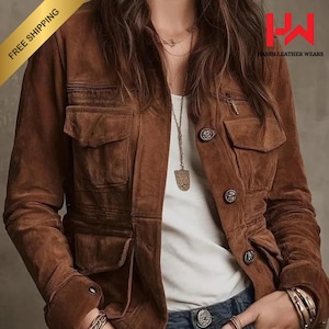 Puede incluir: Chaqueta de ante marrón con múltiples bolsillos, cierres de botón y un bolsillo con cremallera. La chaqueta tiene un diseño clásico y se usa sobre una camiseta blanca. La imagen también incluye el texto "Hassh Leather Wears".