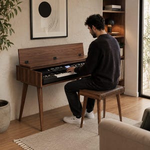 May include: A dark walnut wood digital piano console with a hinged lid, featuring a black keyboard and control panel. The instrument stands on four tapered legs and is accompanied by a matching rectangular wooden bench with a padded seat.