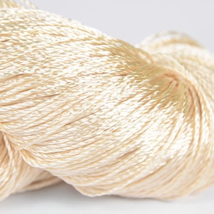 May include: A close-up of a skein of cream-colored embroidery floss.