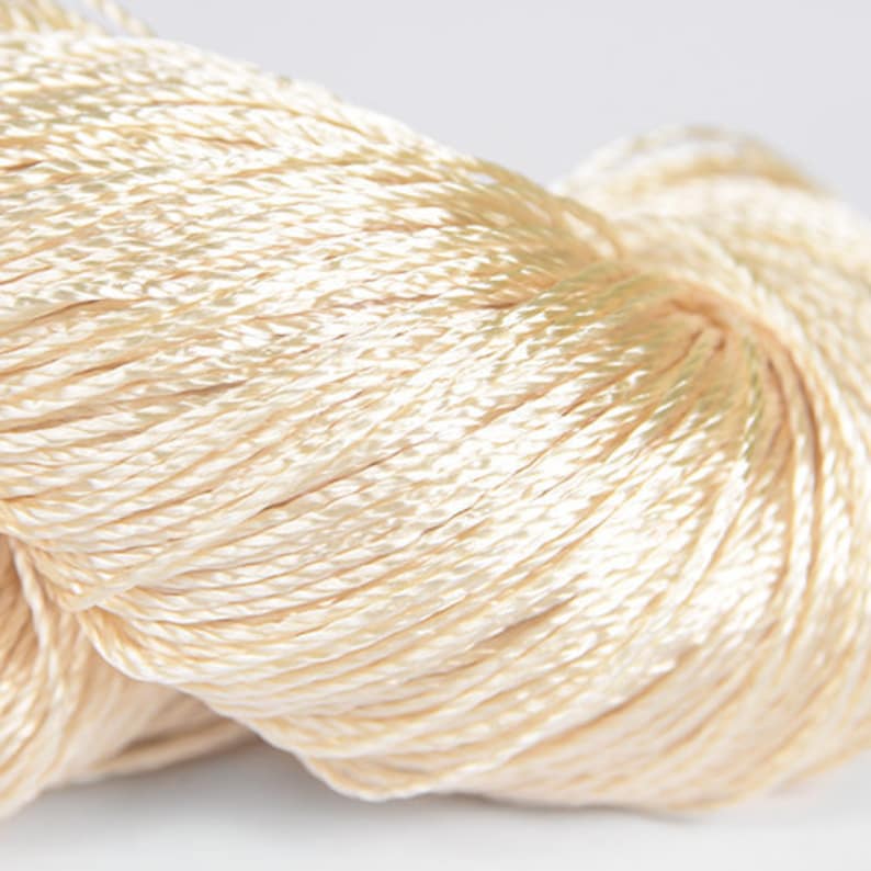 May include: A close-up of a skein of cream-colored embroidery floss.
