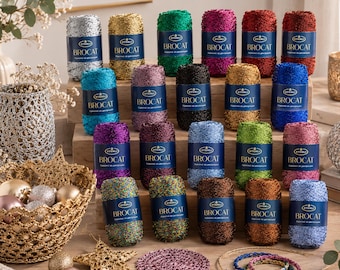 May include: A collection of twenty spools of Stenli Brocat yarn in various metallic colors, each featuring a blue label. The yarn is arranged in rows, accompanied by decorative items including a gold crocheted basket, ornaments, and a circular mat.
