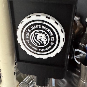 以下が含まれることがあります： 「Mac & Jack's Brewing Co. Redmond, Washington」と書かれた白と黒の円形ロゴとライオンの頭が特徴の黒いタップハンドル。 タップハンドルはビールディスペンシングシステムの一部です。