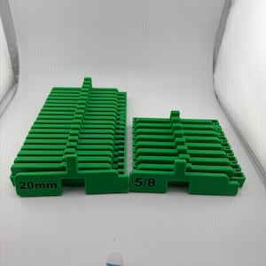 Puede incluir: Dos cuñas de nivelación de plástico verde. Una está etiquetada como "20 mm" y la otra como "5/8". Las cuñas están apiladas en forma rectangular.