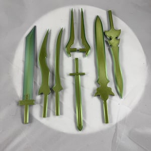 May include: A collection of seven green toy swords with various blade and hilt designs. The swords are arranged on a white surface, showcasing their different shapes and sizes. The blades have a translucent appearance.