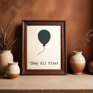 Peut inclure: Une affiche encadrée dans un cadre en bois marron foncé. L'affiche présente une illustration de ballon bleu sarcelle avec une ficelle et le texte "They All Float" en police serif. L'affiche est exposée sur une étagère avec des vases.