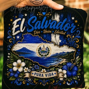 May include: A black square pillow featuring a graphic of El Salvador with the text El Salvador, Dios Union Libertad, and Pura Vida. The design includes a map of the country, the national coat of arms, blue and white flowers, and gold accents.
