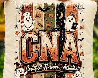 Op de afbeelding: Een vierkant gebroken wit kussen met een grafische print met de tekst CNA Certified Nursing Assistant. Het ontwerp bevat vier spoken, pompoenen, vleermuizen, spinnenwebben en herfstbladeren over verticale strepen in oranje, groen en zwart.