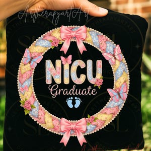 Puede incluir: Cojín negro con un diseño de corona floral. La corona incluye lazos rosas, mariposas y rosas, que rodean las palabras "NICU Graduate" y huellas de bebé. El diseño es en colores pastel.