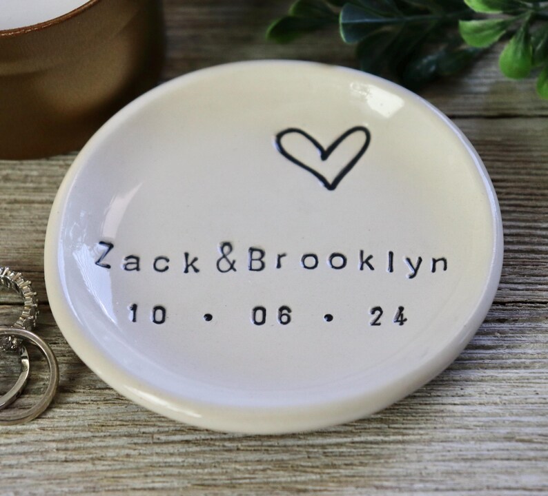 Op de afbeelding: Witte keramische ringenschotel met een handgetekend hart en de tekst "Zack & Brooklyn 10.06.24".