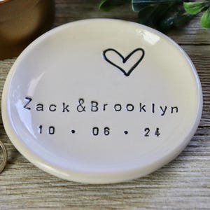 Op de afbeelding: Witte keramische ringenschotel met een handgetekend hart en de tekst "Zack & Brooklyn 10.06.24".