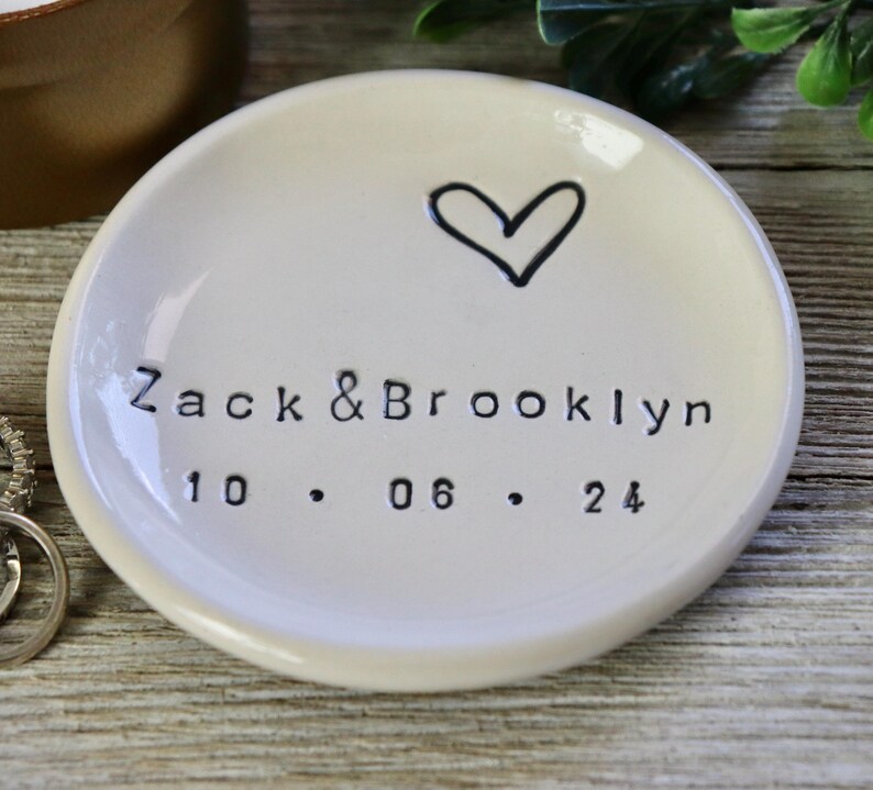 Op de afbeelding: Witte keramische ringenschotel met een handgetekend hart en de tekst "Zack & Brooklyn 10.06.24".