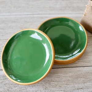 Op de afbeelding: Drie groene keramische sierborden met een gouden rand. De borden zijn op elkaar gestapeld.