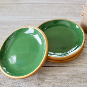 Op de afbeelding: Vier groene keramische sieradenbakjes met een gouden rand. De bakjes zijn op elkaar gestapeld.