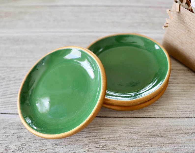 Op de afbeelding: Vier groene keramische sieradenbakjes met een gouden rand. De bakjes zijn op elkaar gestapeld.