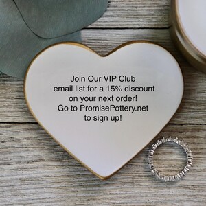 Op de afbeelding: Witte, hartvormige keramische schaal met een gouden rand. De schaal heeft de tekst "Join Our VIP Club email list for a 15% discount on your next order! Go to PromisePottery.net to sign up!"
