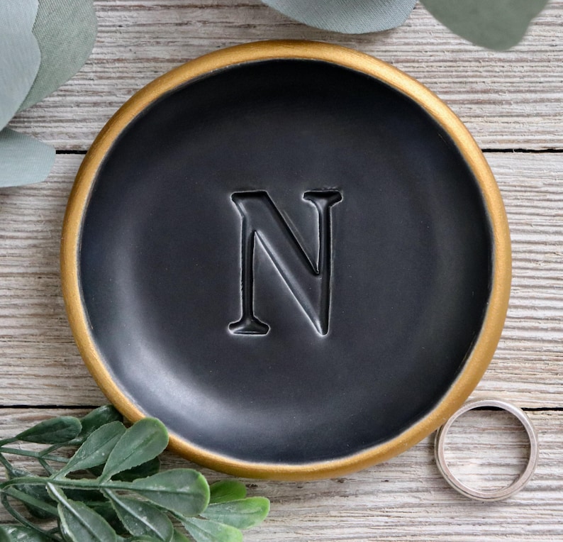 black ring dish sitting on a wood table with branches and leaves.