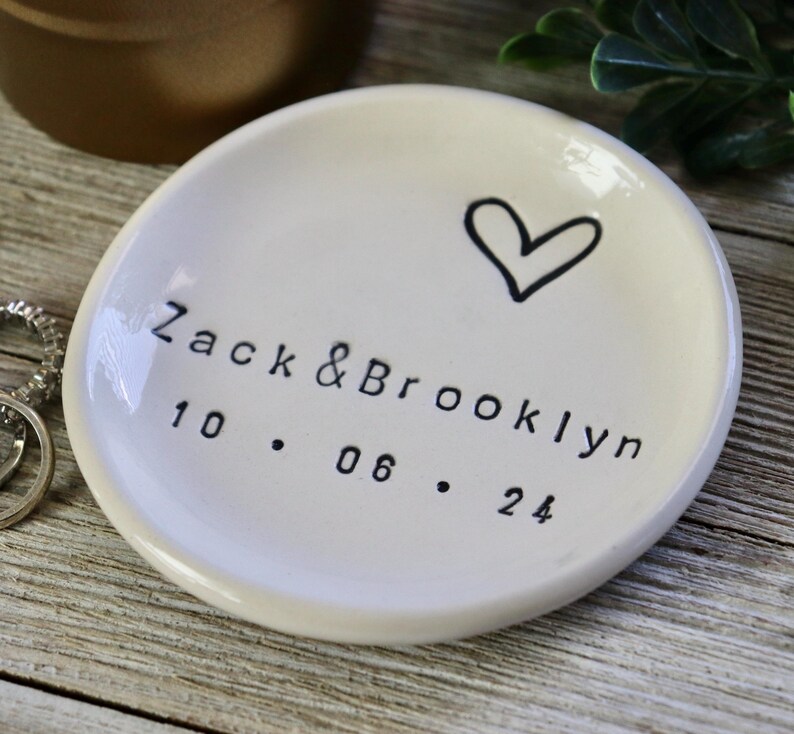 Op de afbeelding: Witte keramische ringenschotel met een handgetekend hart en de tekst "Zack & Brooklyn 10.06.24".