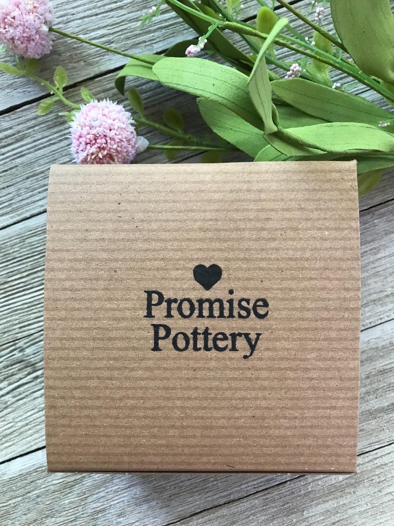 May include: A brown cardboard box with the text "Promise Pottery" and a small heart symbol.