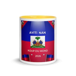 May include: A white ceramic mug with a yellow interior. The mug features the Haitian flag design, with blue and red sections, the Haitian coat of arms, and the text "AYITI NAN" and "KOUP DU MOND 2026".