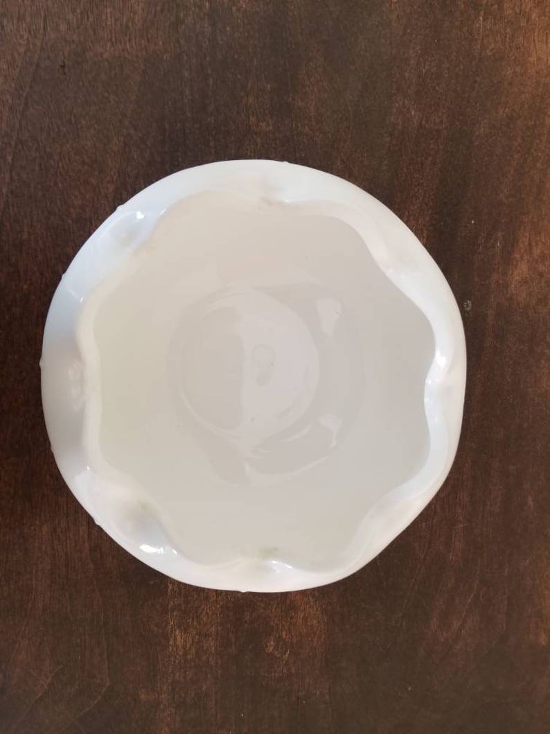 Puede incluir: Un taz&oacute;n de cer&aacute;mica blanco con un borde festoneado. El taz&oacute;n est&aacute; vac&iacute;o y tiene un acabado liso y brillante.