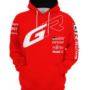 Könnte beinhalten: Roter Kapuzenpullover mit weißem "GR"-Logo und Logos von Rennsponsoren. Verfügt über eine schwarz gefütterte Kapuze und eine Vordertasche. Die Texte "TOYOTA GAZOO Racing", "DENSO", "FUJITSU" und "Mobil" sind sichtbar.