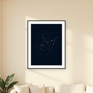 May include: A framed vertical wall art print featuring a dark navy blue background with a gold constellation map. The celestial design displays interconnected stars and points of light arranged in a specific pattern, enclosed within a thin black frame.