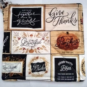 May include: A quilted pot holder with a patchwork design featuring a variety of fall-themed patterns and text. The text includes "Gather Together and Be Grateful", "Give Thanks", "Grateful", "Hand-Picked Pumpkins Fresh and Local Pick Your Own", "Give Thanks", and "Bless The Food Before Us The Family Beside Us The Love Between Us".