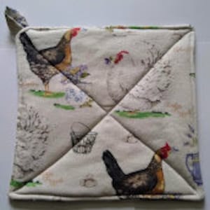 May include: A square, white cotton pot holder with a pattern of brown and white chickens, green grass, and a basket. The pot holder has a loop for hanging.