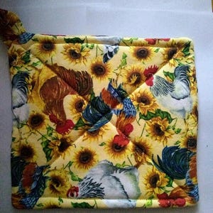 May include: A yellow quilted hot pad with a pattern of roosters, sunflowers, and green leaves. The hot pad has a loop handle.