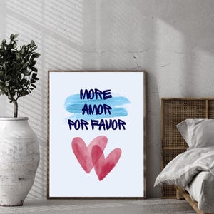 Peut inclure: Impression d'art encadrée avec l'inscription "MORE AMOR FOR FAVOR" en bleu foncé, au-dessus de deux cœurs rouges à l'aquarelle. Le fond est bleu clair avec un coup de pinceau bleu. L'impression est dans un cadre marron.