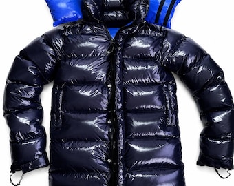May include: A navy blue puffer jacket with a shiny, glossy finish. The jacket has a bright blue hood lining and a full-length zip. The design includes a high collar and side pockets, with drawstrings at the hem and cuffs.