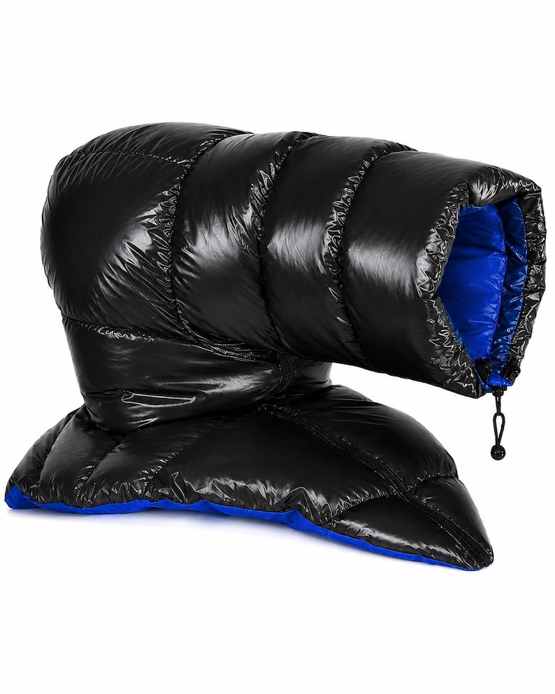 K&ouml;nnte beinhalten: Ein gl&auml;nzendes, schwarzes, gestepptes Puffer-Accessoire mit leuchtend blauem Innenfutter. Der Artikel hat eine r&ouml;hrenf&ouml;rmige, gepolsterte Konstruktion mit horizontalen N&auml;hten und einen schwarzen Kordelzugverschluss an der &Ouml;ffnung.