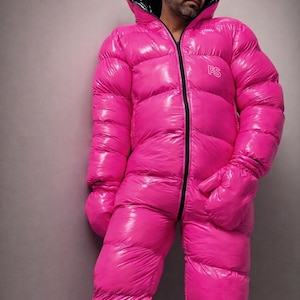 May include: A vibrant pink, padded jumpsuit featuring a black zip and hood trim. The jumpsuit includes attached mittens and the letters "PS" on the chest. The garment is made of a shiny, quilted material.