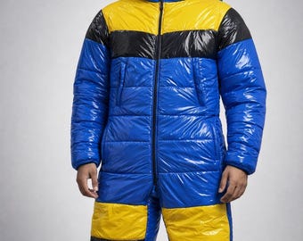 May include: A blue, yellow, and black quilted snowsuit with a hood and a front zipper. The snowsuit is made of a shiny, water-resistant material. The design features horizontal stripes of yellow and black across the chest and legs.