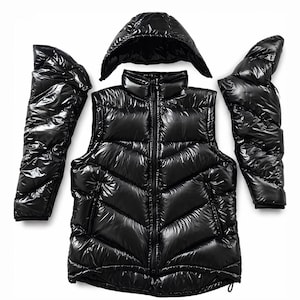 May include: A black puffer vest with a matching hood and detachable sleeves. The vest has a high collar and a full-length zipper. The glossy material reflects light, creating a shiny appearance. The sleeves are separate, allowing for versatility in wear.