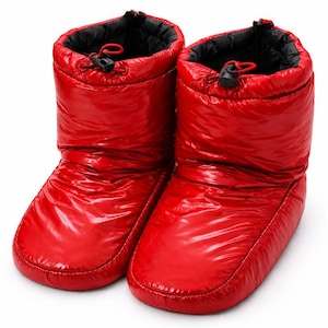 Puede incluir: Un par de botas rojas brillantes y acolchadas. Las botas tienen una textura brillante y acolchada y un forro negro en la parte superior. Cada bota tiene un cierre de cordón con un cordón rojo y una presilla negra.