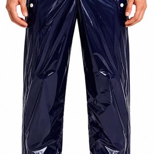 Puede incluir: Pantalones impermeables azul marino brillante con detalles de botones blancos a lo largo de las costuras laterales. Los pantalones tienen cintura elástica y están fruncidos en los tobillos. El material tiene un aspecto arrugado.