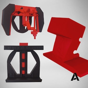 May include: Three 3D printed objects in red and black. One is a red and black mechanical assembly, another is a black stand with the text GYRODRIVE and a red threaded rod, and the third is a solid red angled block with a letter A logo.