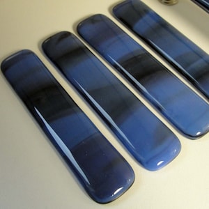 May include: Four blue glass cabinet pulls with a white marbled pattern. The pulls are rectangular and have a smooth, glossy finish.