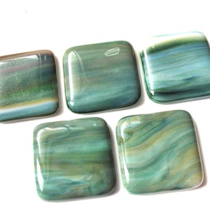 May include: Five square-shaped glass tiles with a swirled pattern of blue, green, and brown colors.