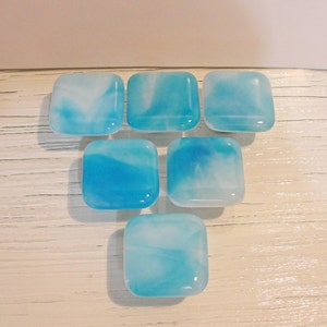 May include: Seven square glass tiles with a blue and white marbled design. The tiles are arranged in a staggered pattern.