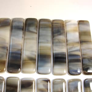 May include: A set of 10 rectangular glass tiles with a swirled pattern in shades of gray, white, and brown. The tiles are arranged in two rows of five.