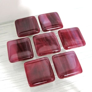 May include: Seven square glass cabinet knobs with a burgundy and purple swirl pattern.