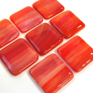 May include: Eight square glass tiles with a red and white swirled pattern. The tiles are glossy and have a translucent appearance.