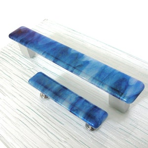 May include: Two blue glass cabinet door pulls with silver hardware. The glass has a marbled effect with white and blue swirls.